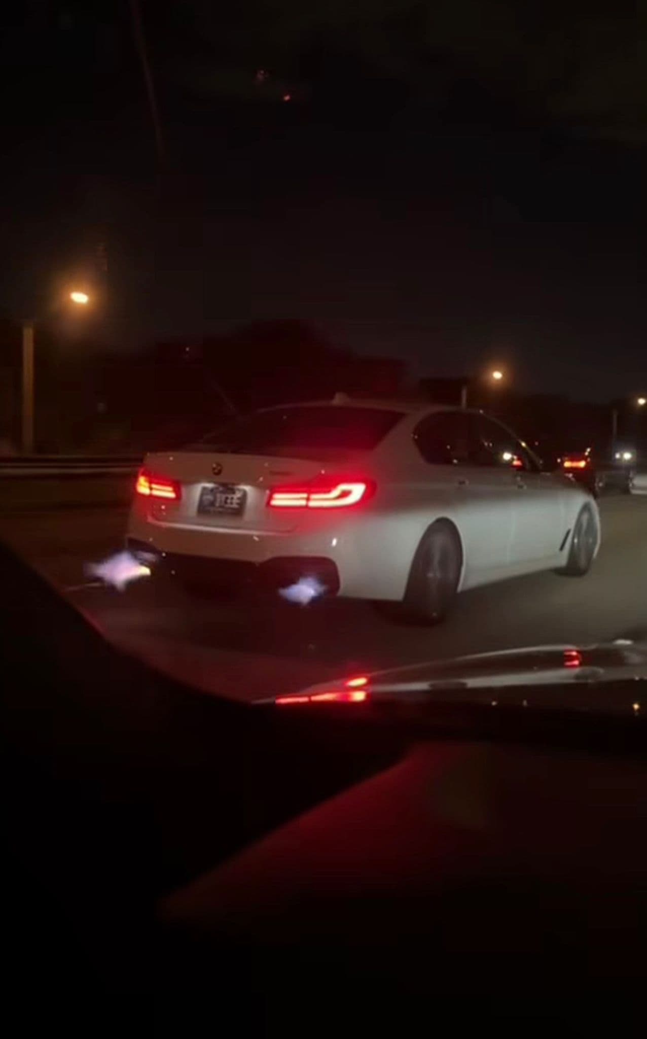 White BMW 540i xDrive cracking flames from twin exhausts on a US highway