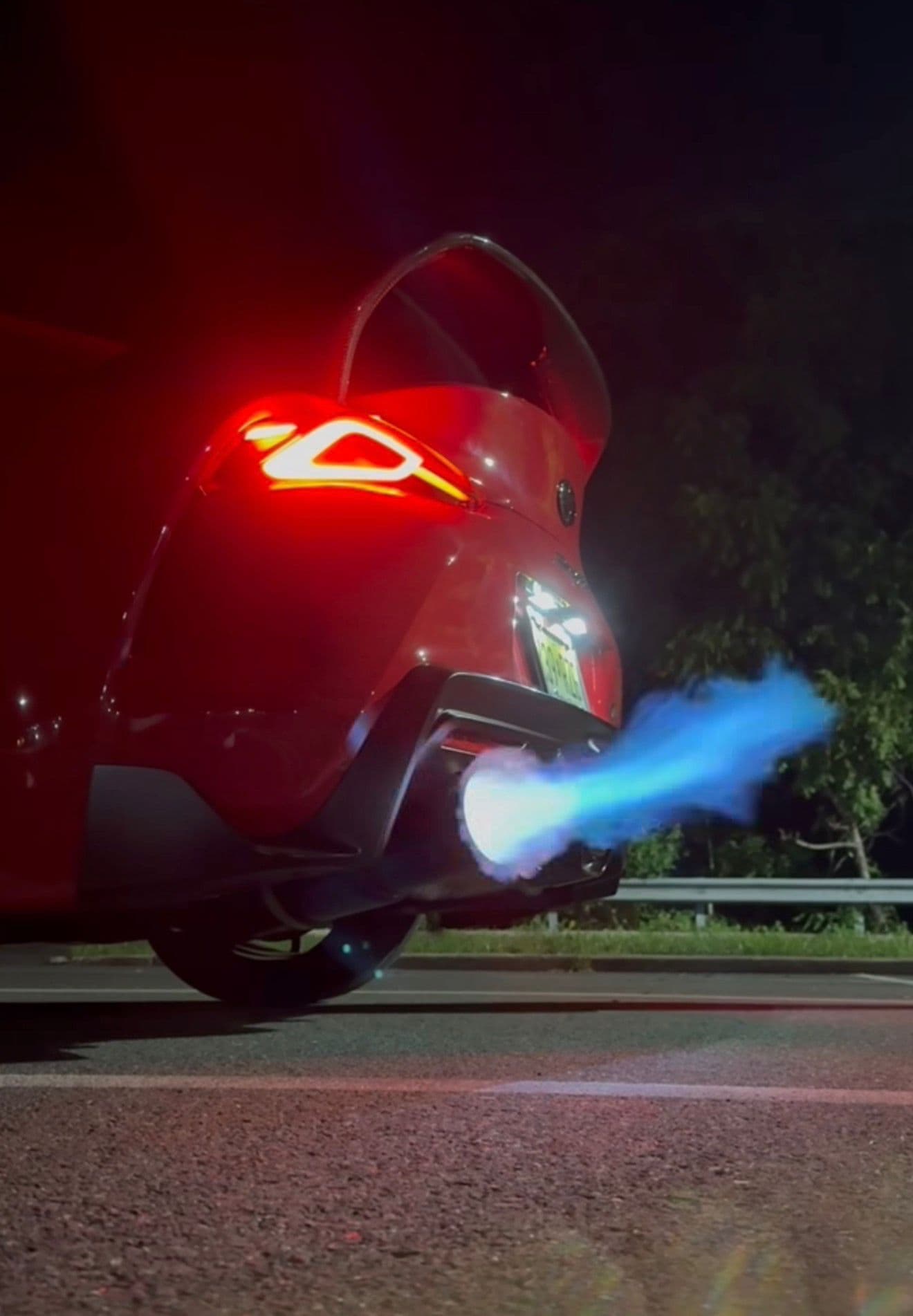 Red Toyota A90 Supra venting a massive blue flame from the side exhaust