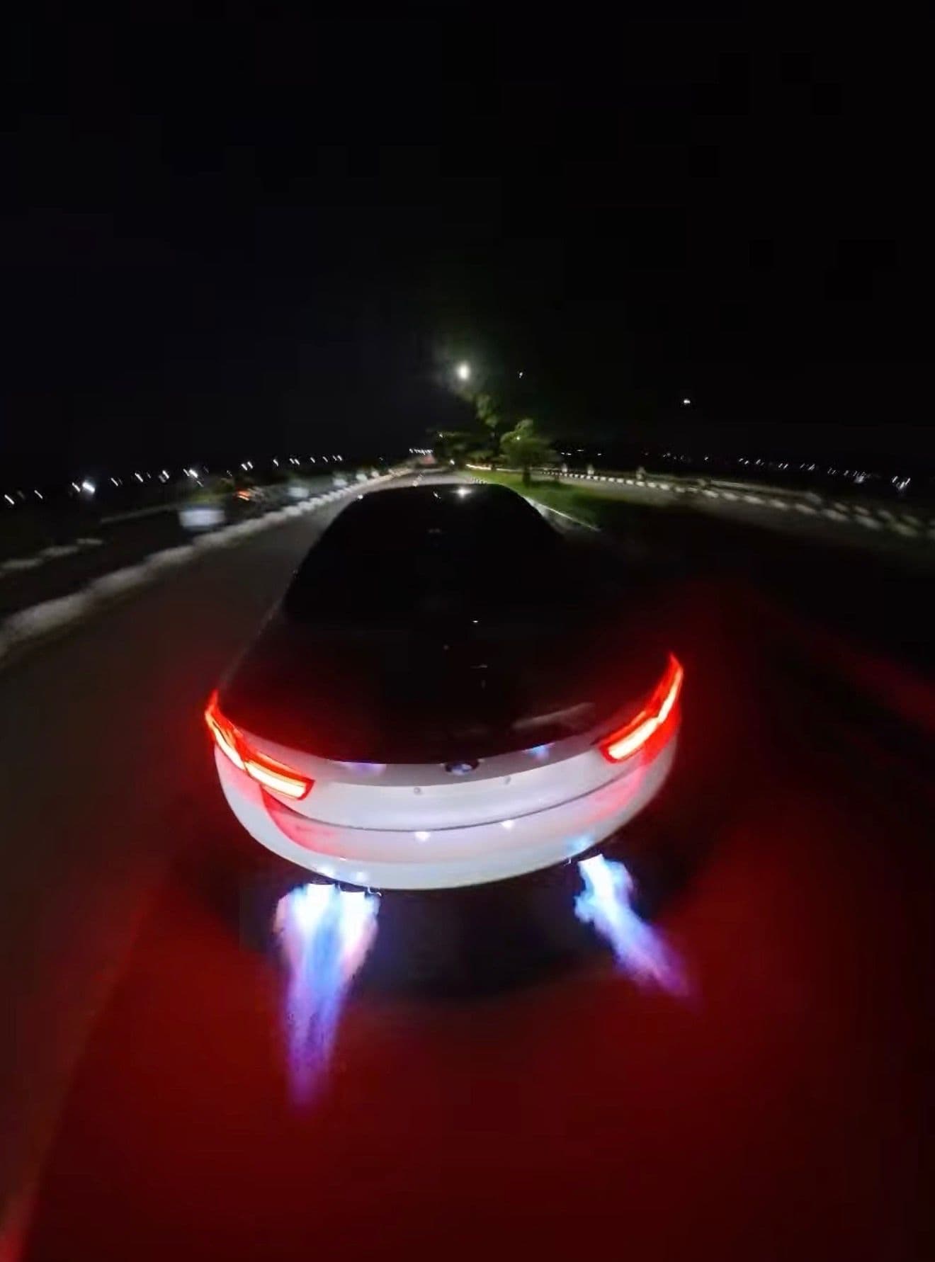 Black BMW 440i cracking blue flames from twin exhausts on a night highway in Taiwan